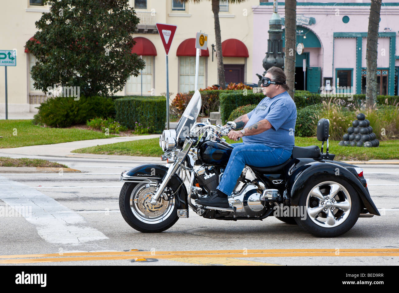 Homme en surpoids conduisant une moto à trois roues à travers le centre-ville St. Augustine, Floride, États-Unis Banque D'Images