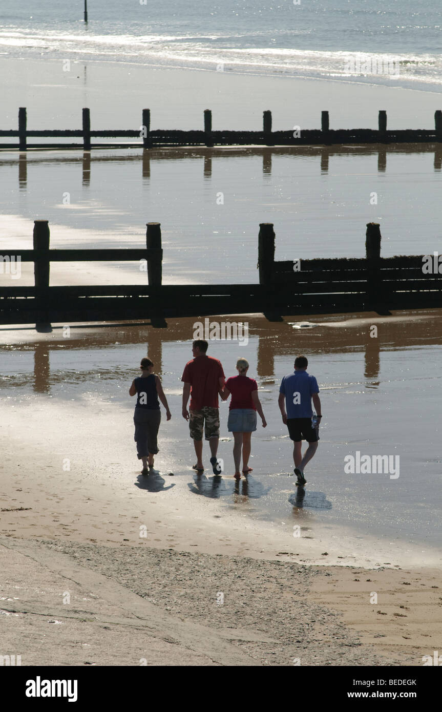 Après-midi de septembre- quatre jeunes gens marchant le long de la plage de sable à Tywyn Gwynedd North Wales UK Banque D'Images