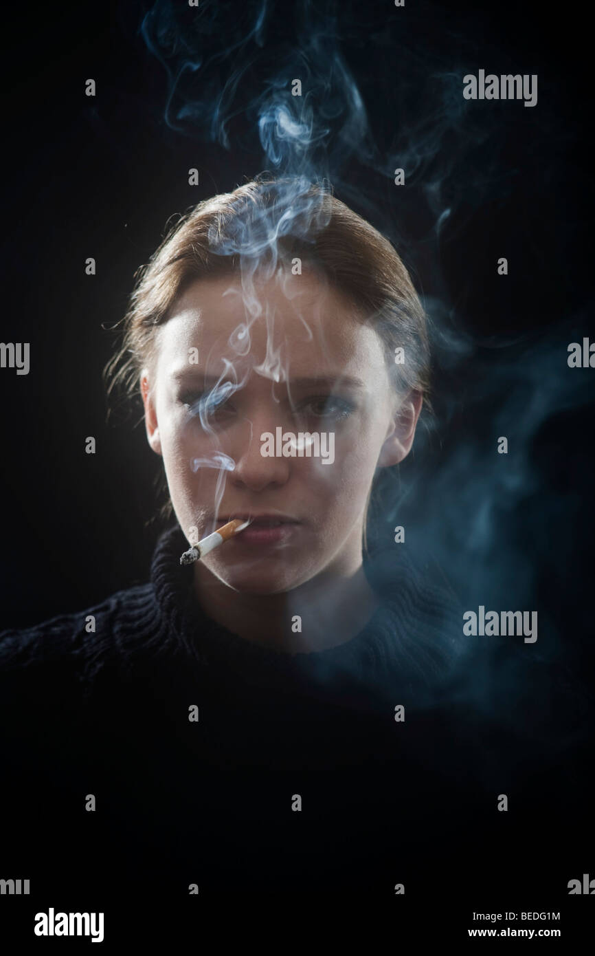 Portrait d'une jeune femme fumant une cigarette, la fumée Banque D'Images