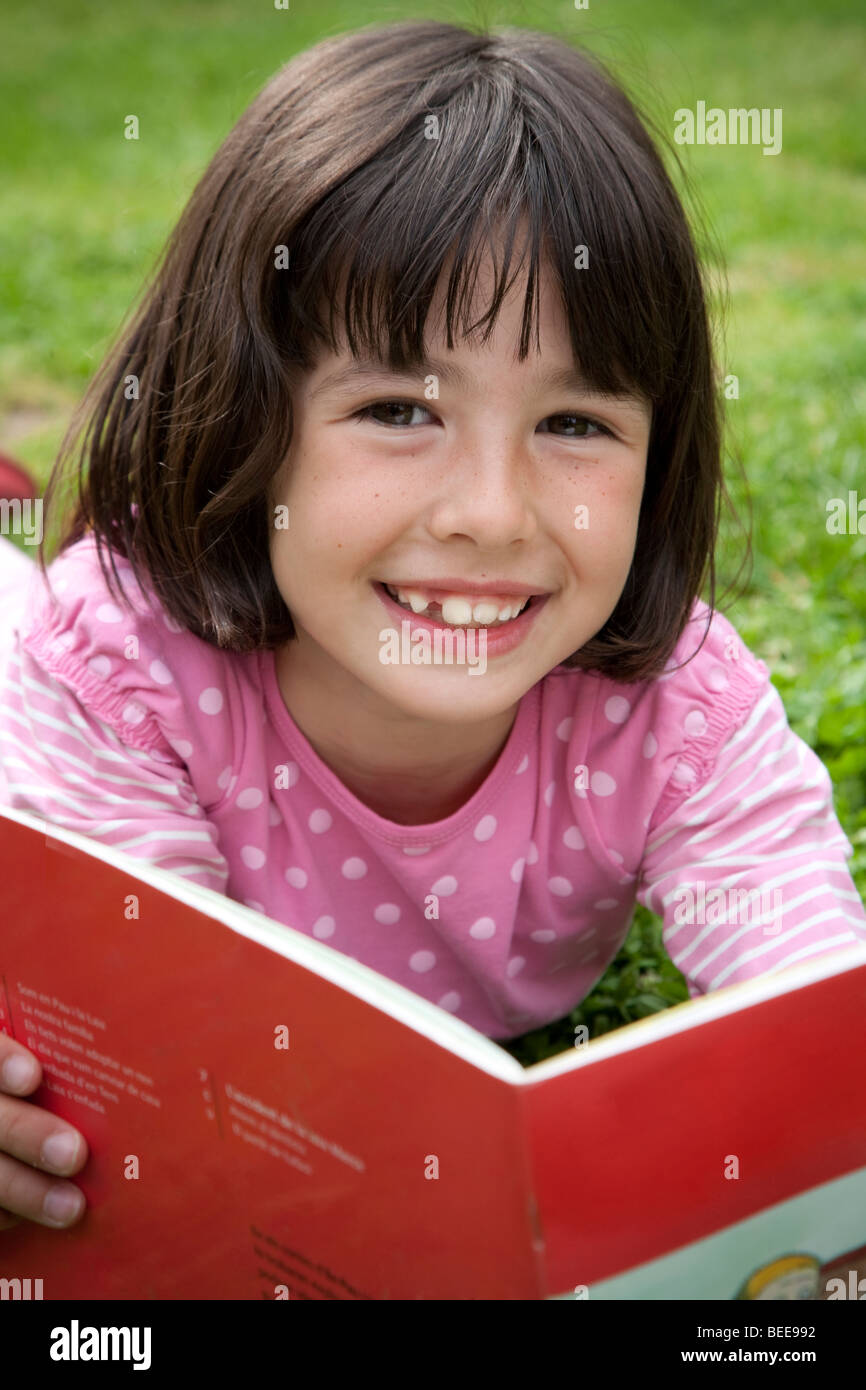 Petite fille lisant au parc Banque D'Images