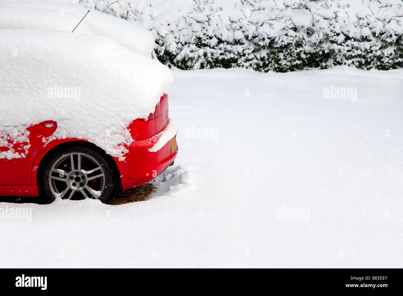 Arrière d'une voiture rouge couverts après une chute de neige récente Banque D'Images