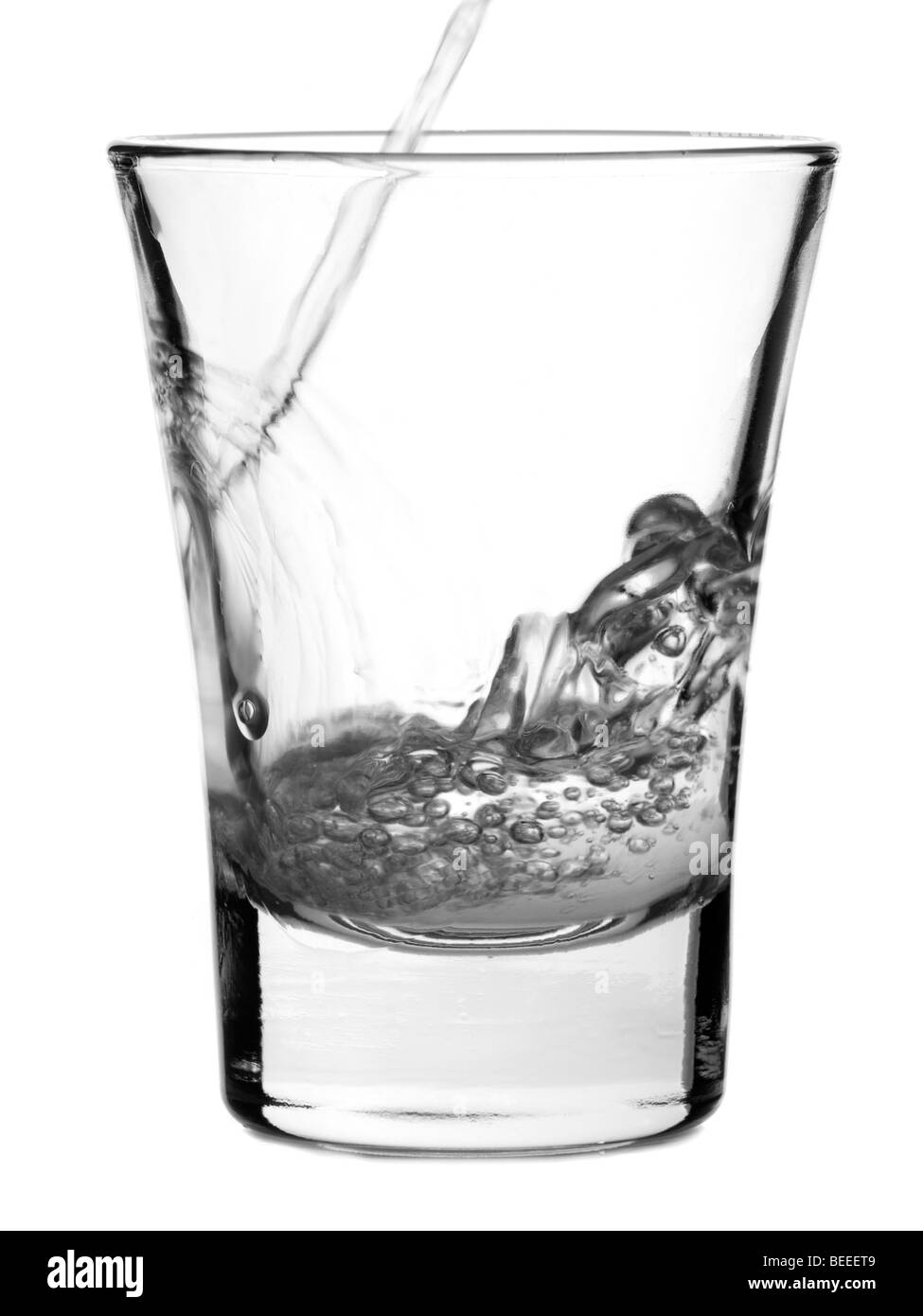 Verser un shot de vodka sur un fond blanc. Banque D'Images