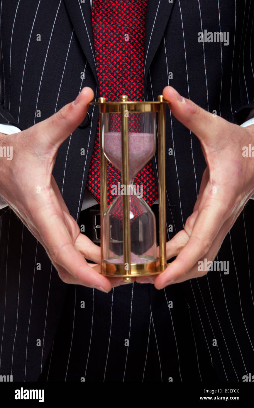 Close up shot of a businessman holding a sable en laiton ou minuteur sablier Banque D'Images