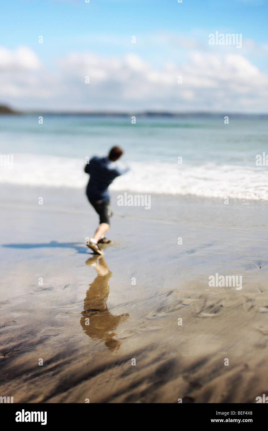 Man on beach l'écrémage des pierres dans la mer Banque D'Images