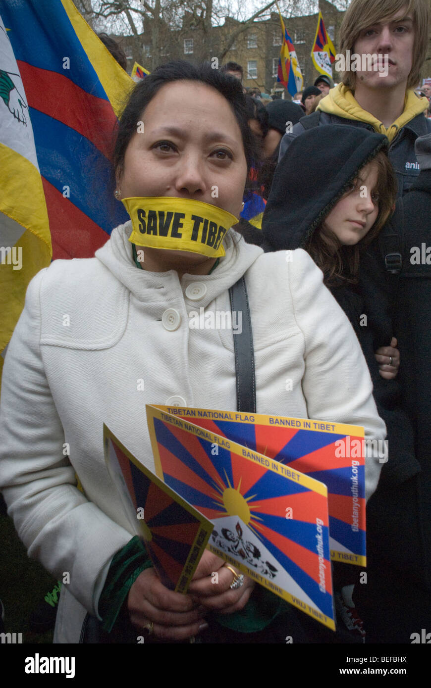 Femme tibétaine avec 'Save' Tibet TIbet libre gag et les drapeaux à relais de la flamme tibétaine de la liberté à Londres Banque D'Images