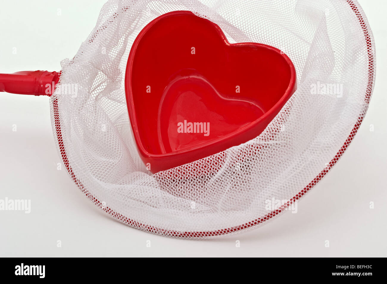 Bonbonnière en forme de cœur rouge dans un filet à papillons Banque D'Images