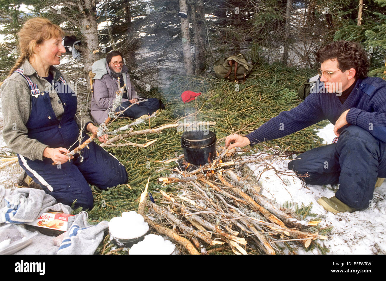 Deux hommes et une femme se détendre en hiver à un "faire bouillir jusqu' à long terme pour Terre-Neuve, un pique-nique. Banque D'Images
