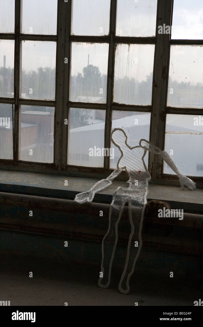 Modèle des droits de l'homme sur le fil figure sur la fenêtre de l'usine abandonnée Banque D'Images