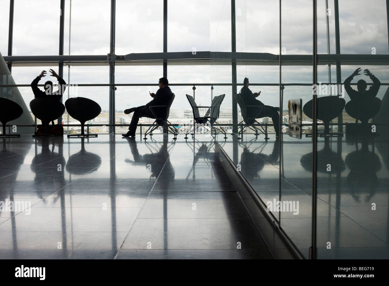 Les silhouettes des passagers au départ et à l'encontre de la forte lumière naturelle provenant des vastes fenêtres d'Heathrow Terminal 5 Banque D'Images
