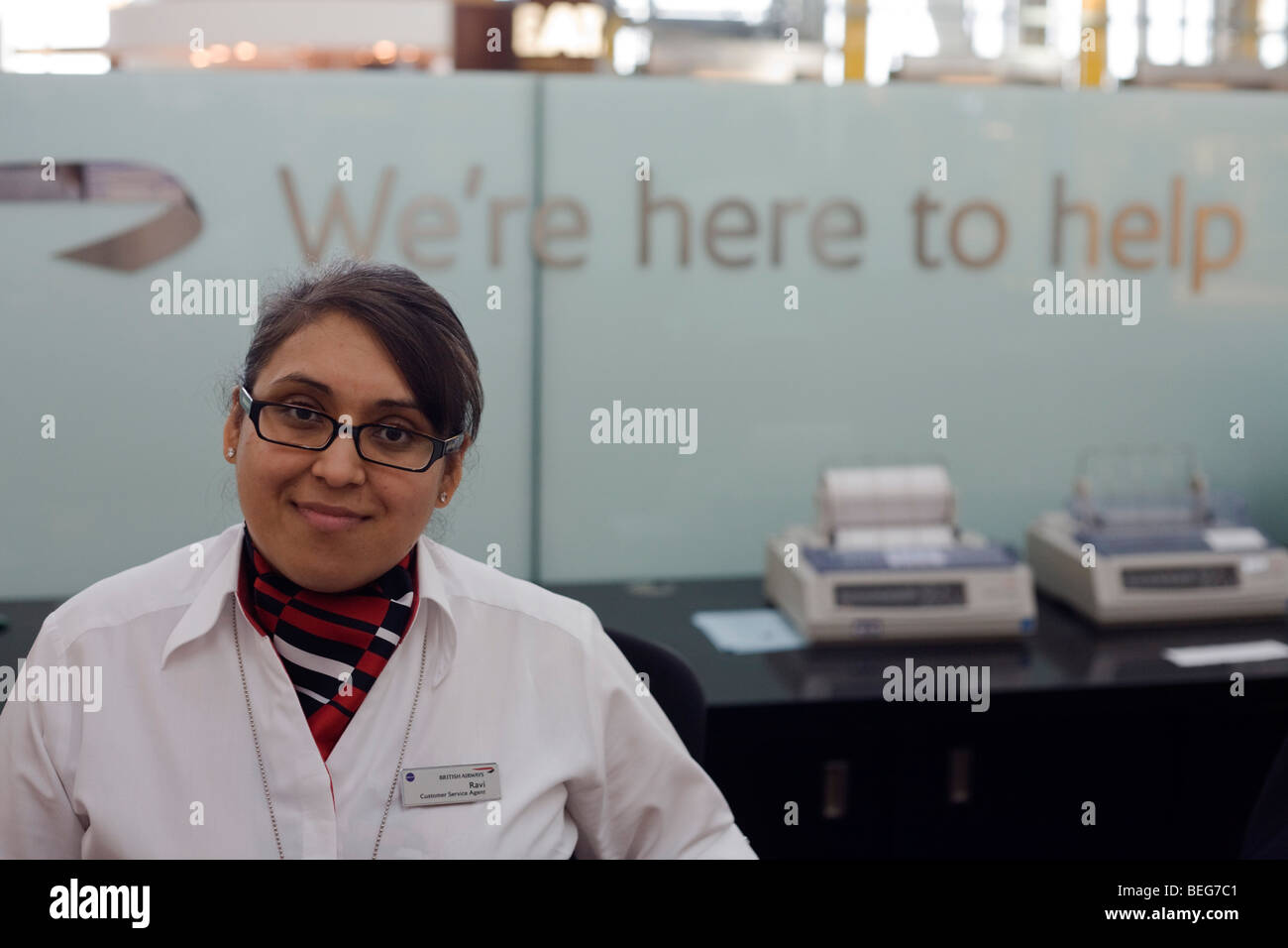 A smiling female membre du personnel au bureau d'information de la British Airways au départ à l'aéroport d'Heathrow Terminal 5. Banque D'Images