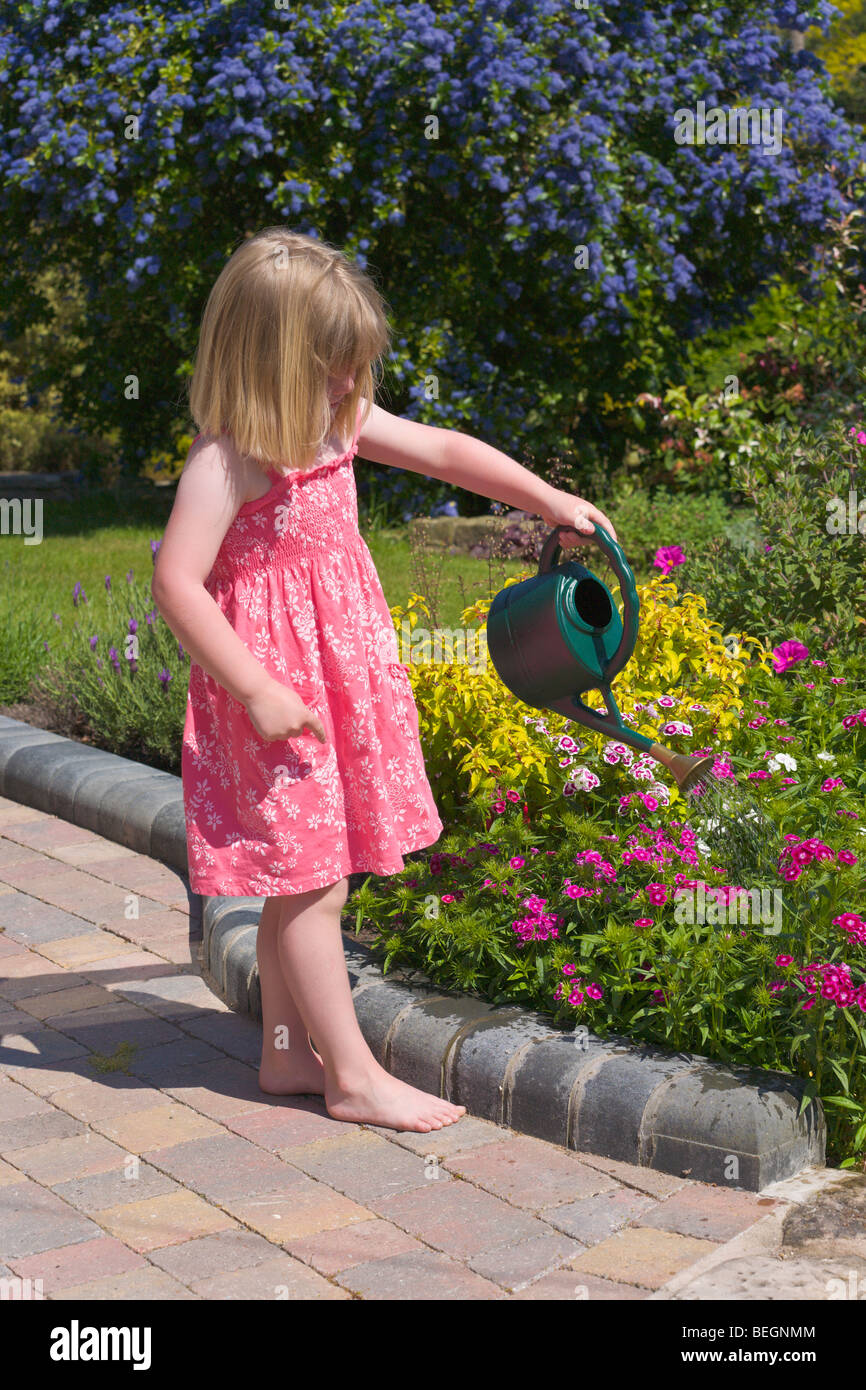 Jeune fille arrosage des fleurs dans un jardin Banque D'Images
