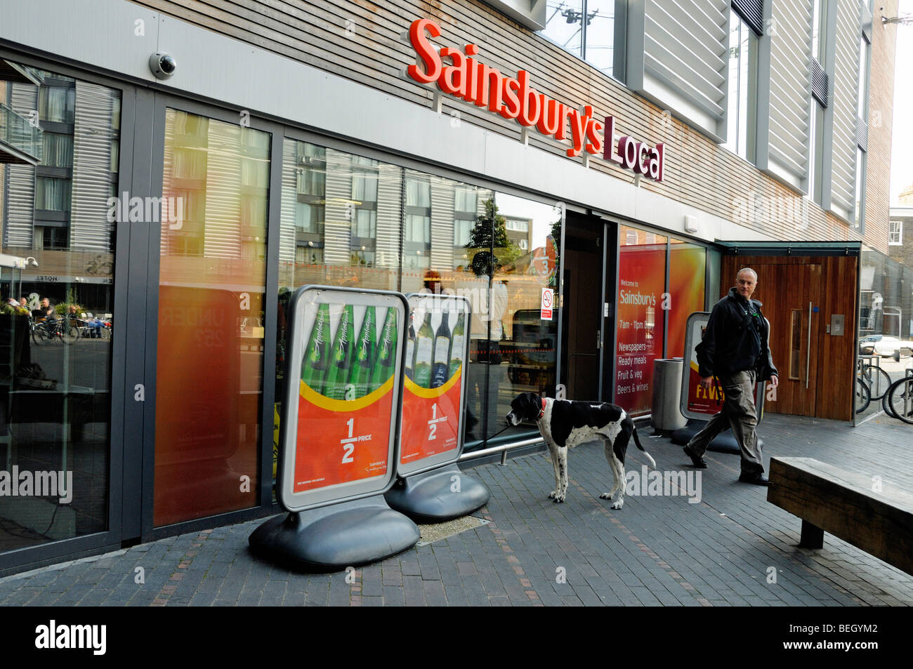 Laissant l'homme et le chien Local Sainsbury's lecture apparemment advertisment Banque D'Images