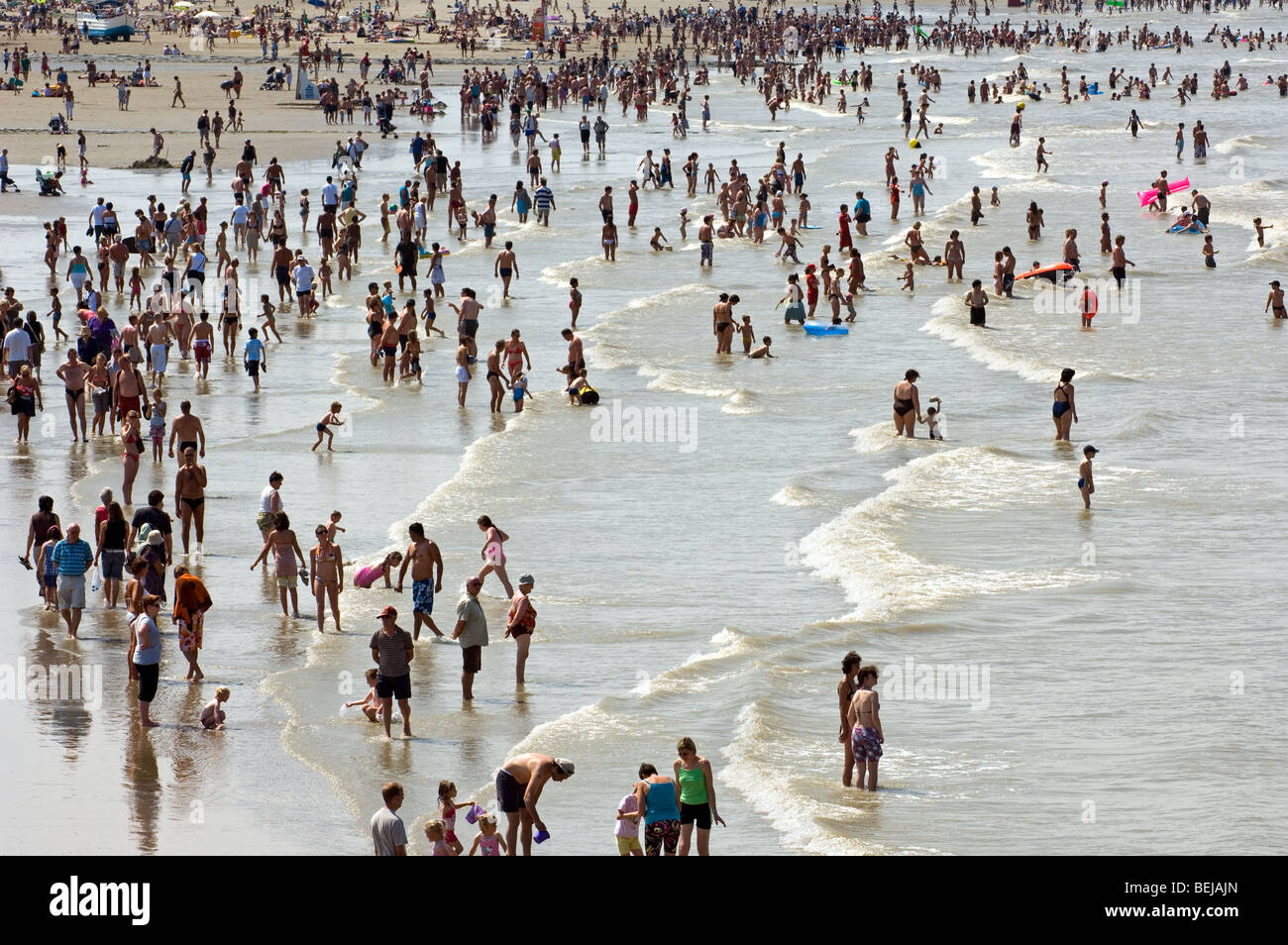 Les touristes en maillot de bain sur la plage bondée pagayer dans la mer du Nord sur une journée chaude pendant les vacances d'été Banque D'Images