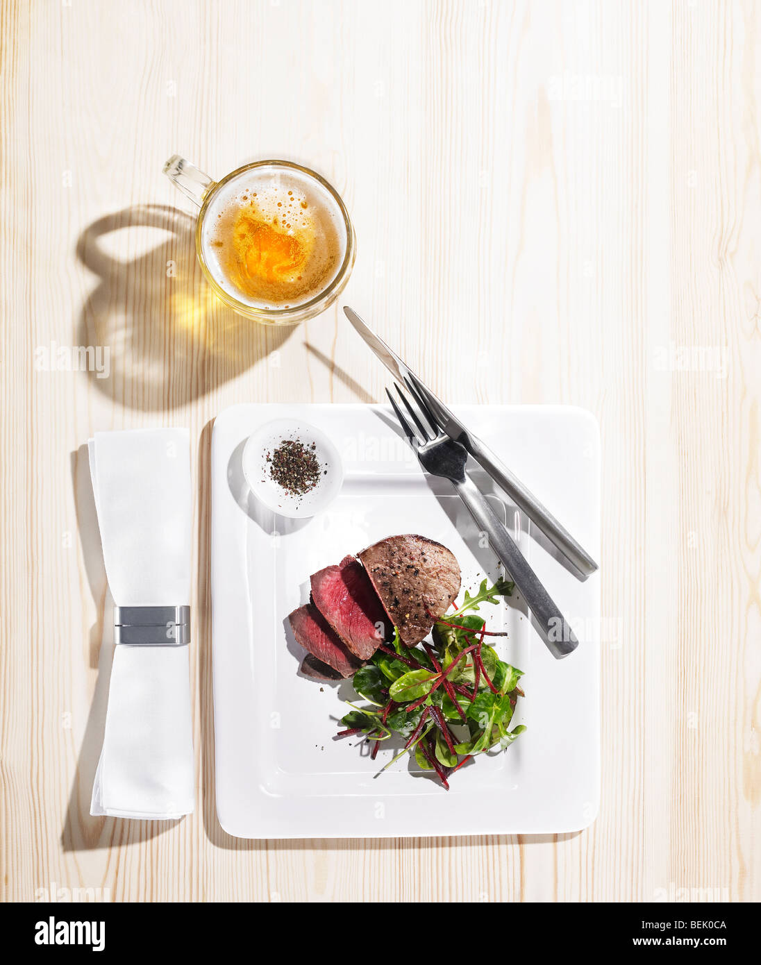 Rôti de bœuf servi avec une salade d'épinards et betteraves, de poivre noir et d'une pinte de bière Banque D'Images