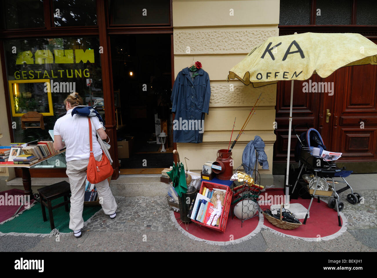 Berlin. L'Allemagne. L'exploration d'une femme un magasin d'objets d'occasion à Prenzlauer Berg. Banque D'Images