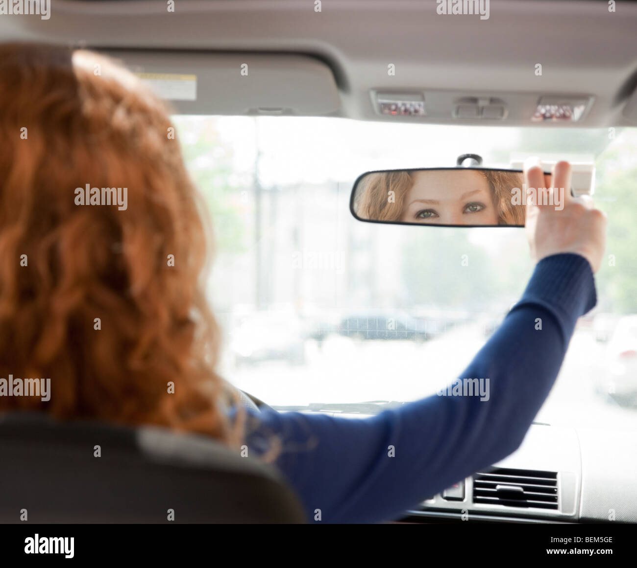 Femme au volant de réglage mirror Banque D'Images