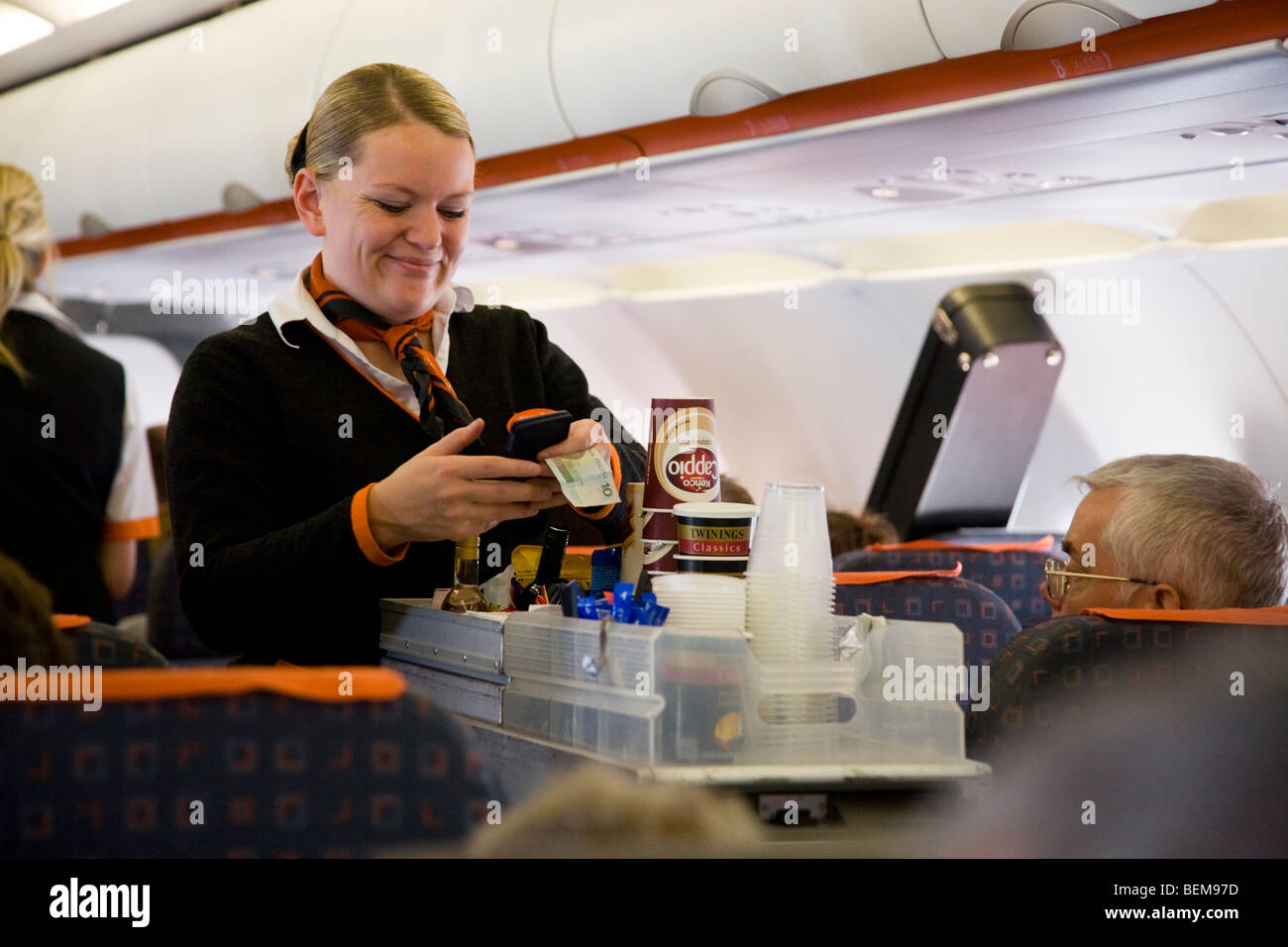 L'équipage de cabine / hôtesse de l'air sert des boissons et des collations à des passagers d'un trolley panier lors d'un vol Easyjet Banque D'Images