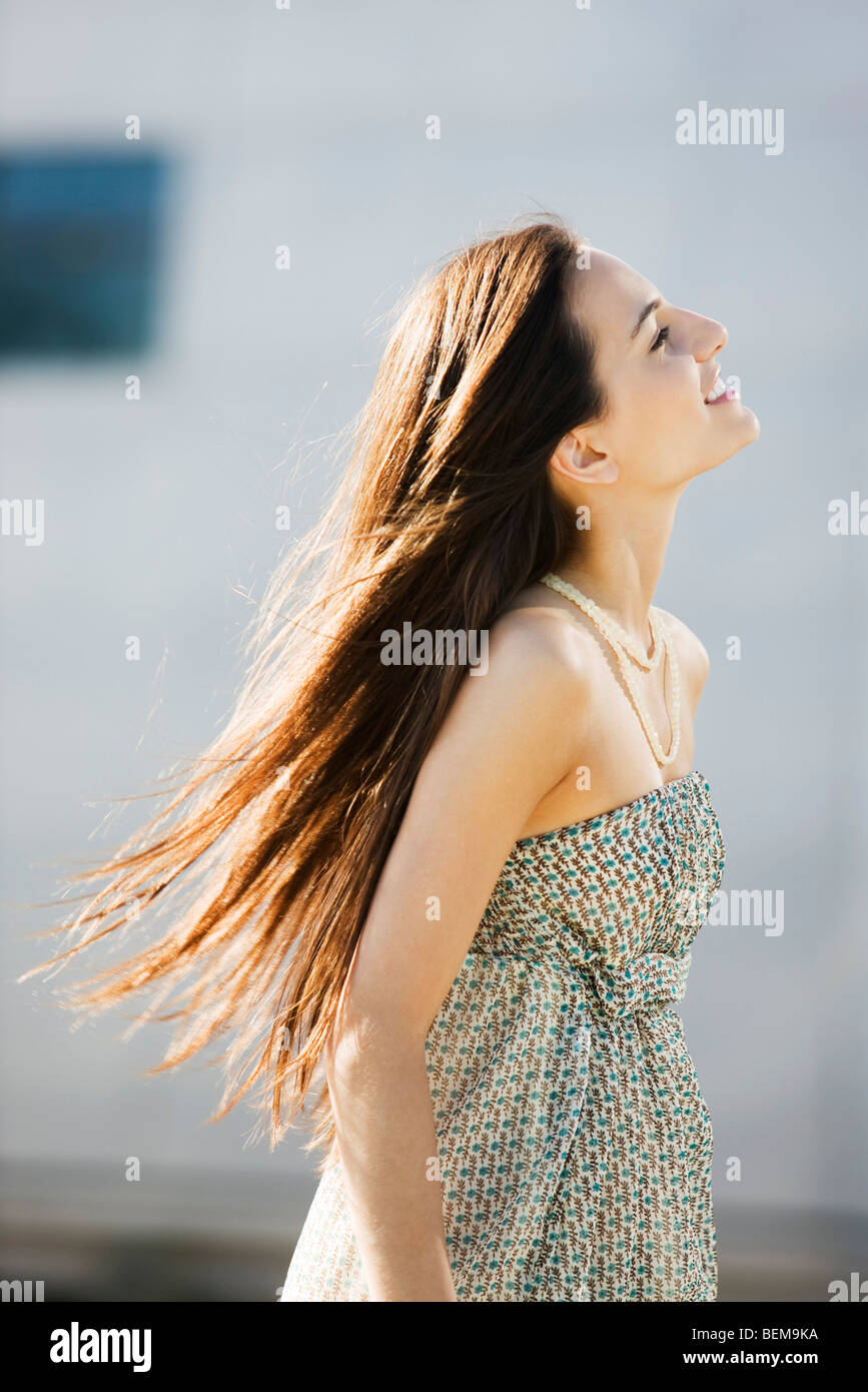 Jeune femme la marche à l'extérieur, de longs cheveux ébouriffés par le vent Banque D'Images