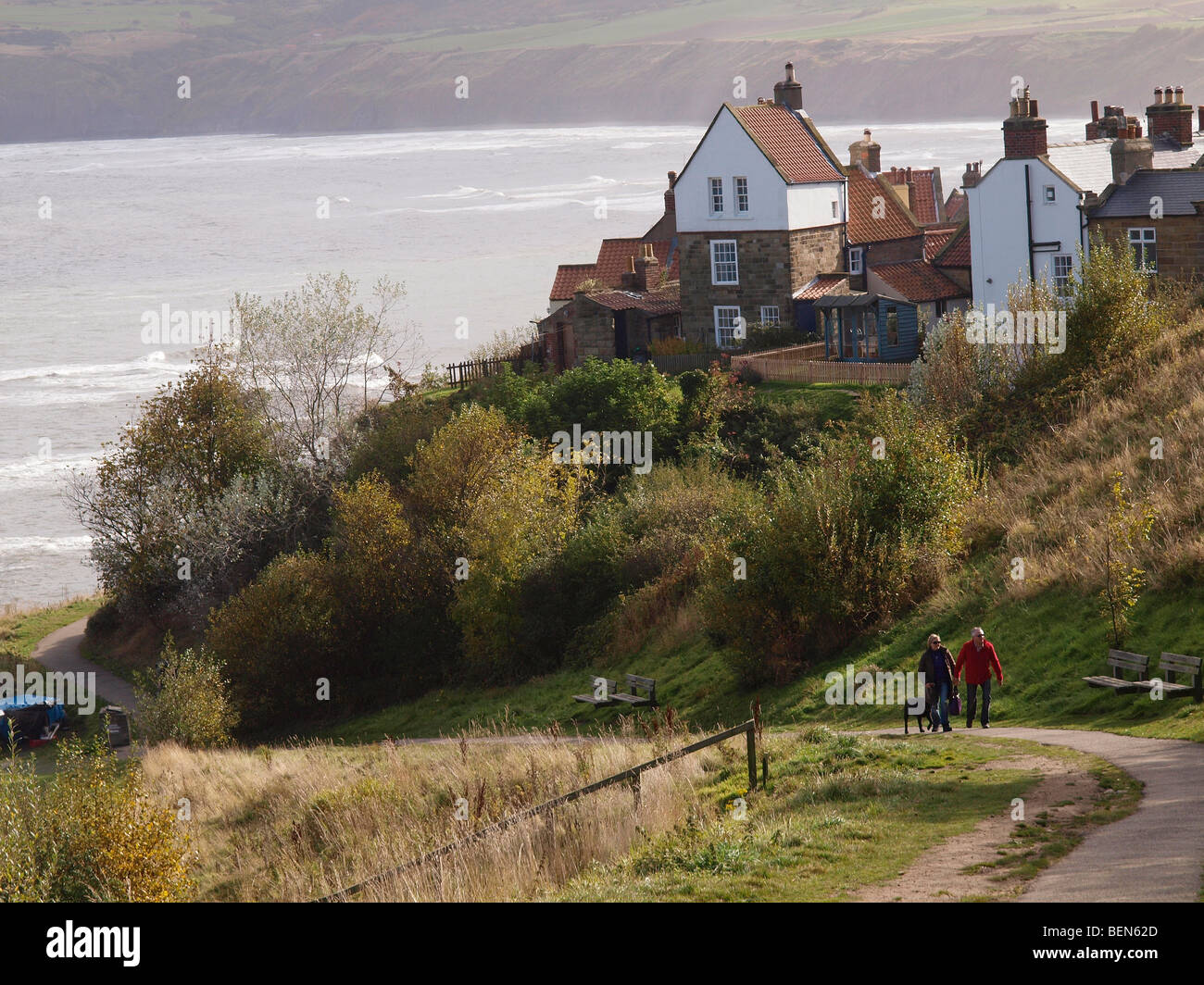Un couple avec un chien Labrador sur l'approche de la pittoresque village de Robin Hood's Bay North Yorkshire, UK Banque D'Images
