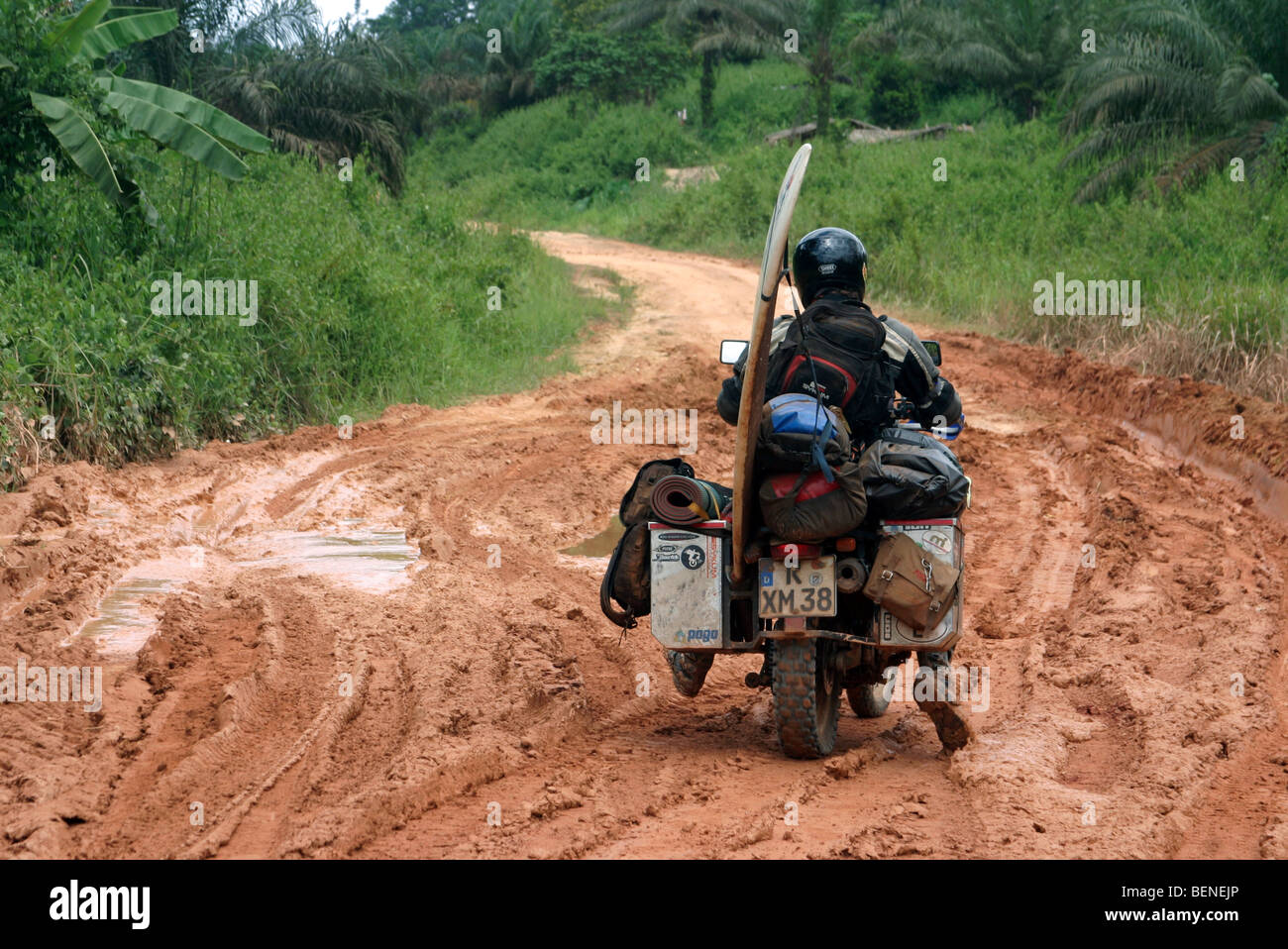 Paniers lourdement un motard avec surf équitation en vélo dans la boue du chemin de terre pendant la saison des pluies, le Gabon, l'Afrique Centrale Banque D'Images