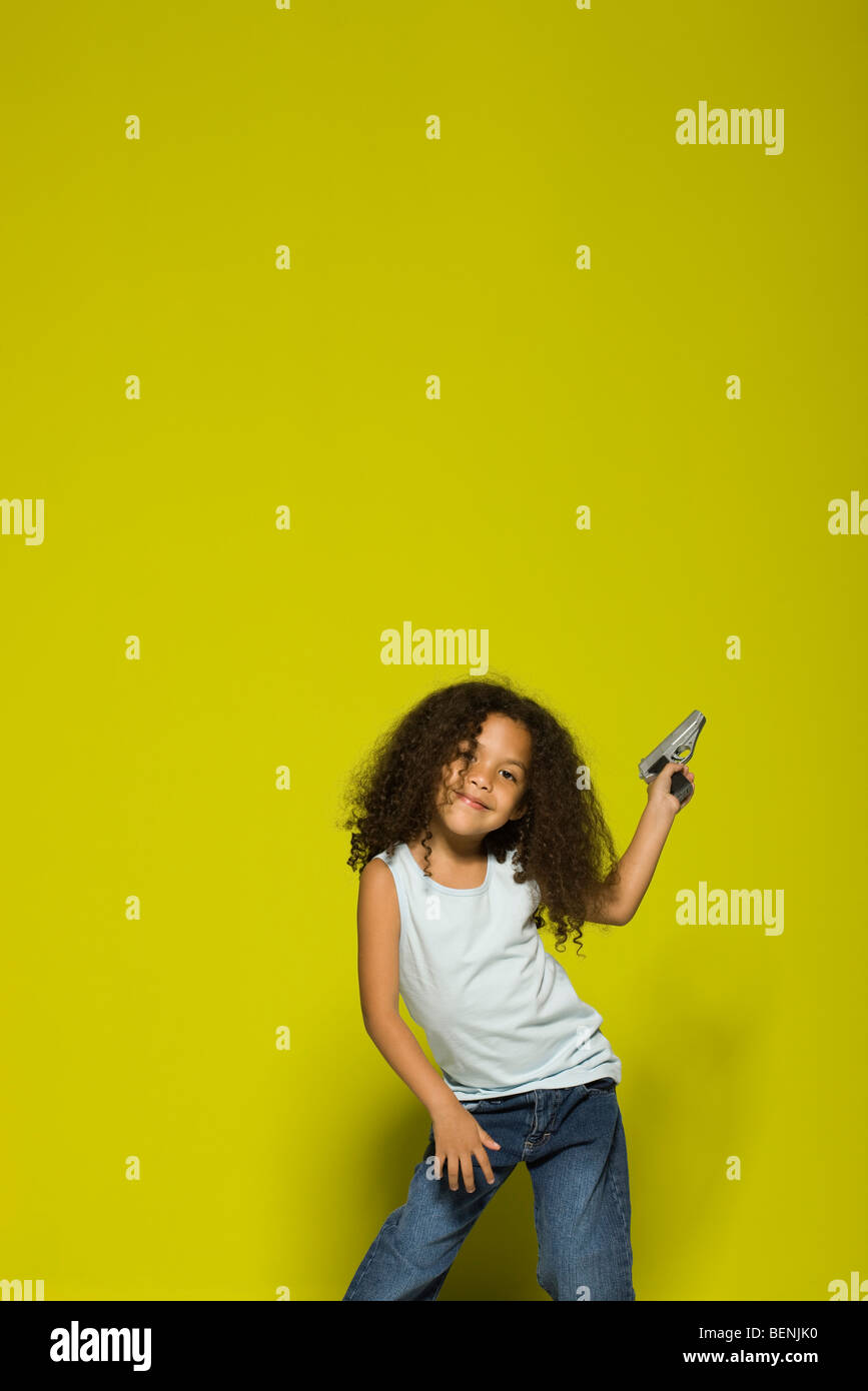 Petite fille posant avec un pistolet jouet Banque D'Images