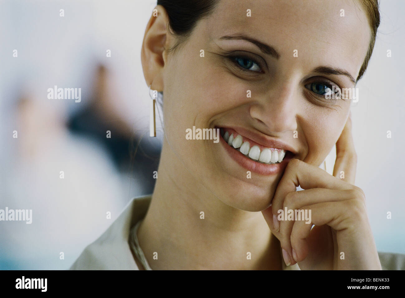 Young woman smiling at camera, penché face contre la main, portrait Banque D'Images