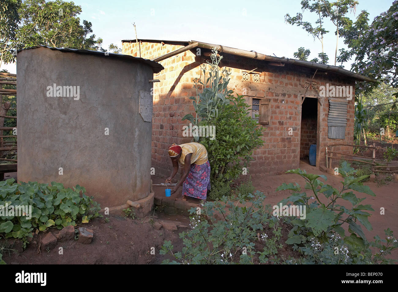 Femme de l'Ouganda la collecte de l'eau potable à partir du réservoir de pluie Banque D'Images