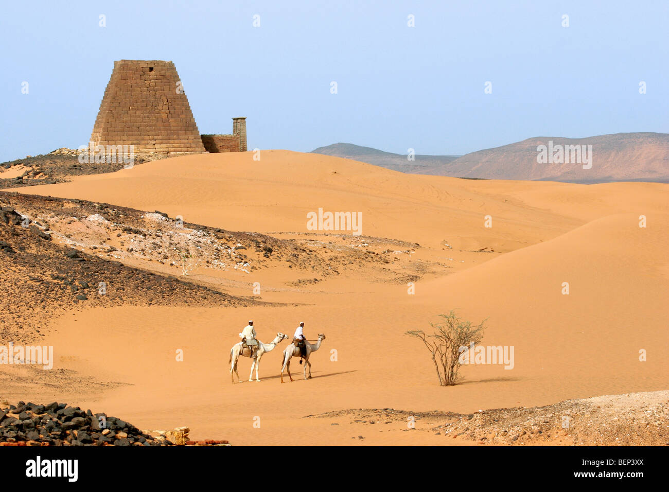 Pyramides de Méroé et deux hommes habillés en Nubie thawbs équitation des dromadaires dans le désert de Nubie du Soudan, l'Afrique du Nord Banque D'Images