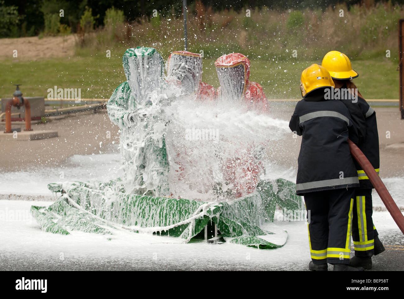 Pompiers en combinaisons étanches aux gaz d'être arrosé avec de la mousse Banque D'Images