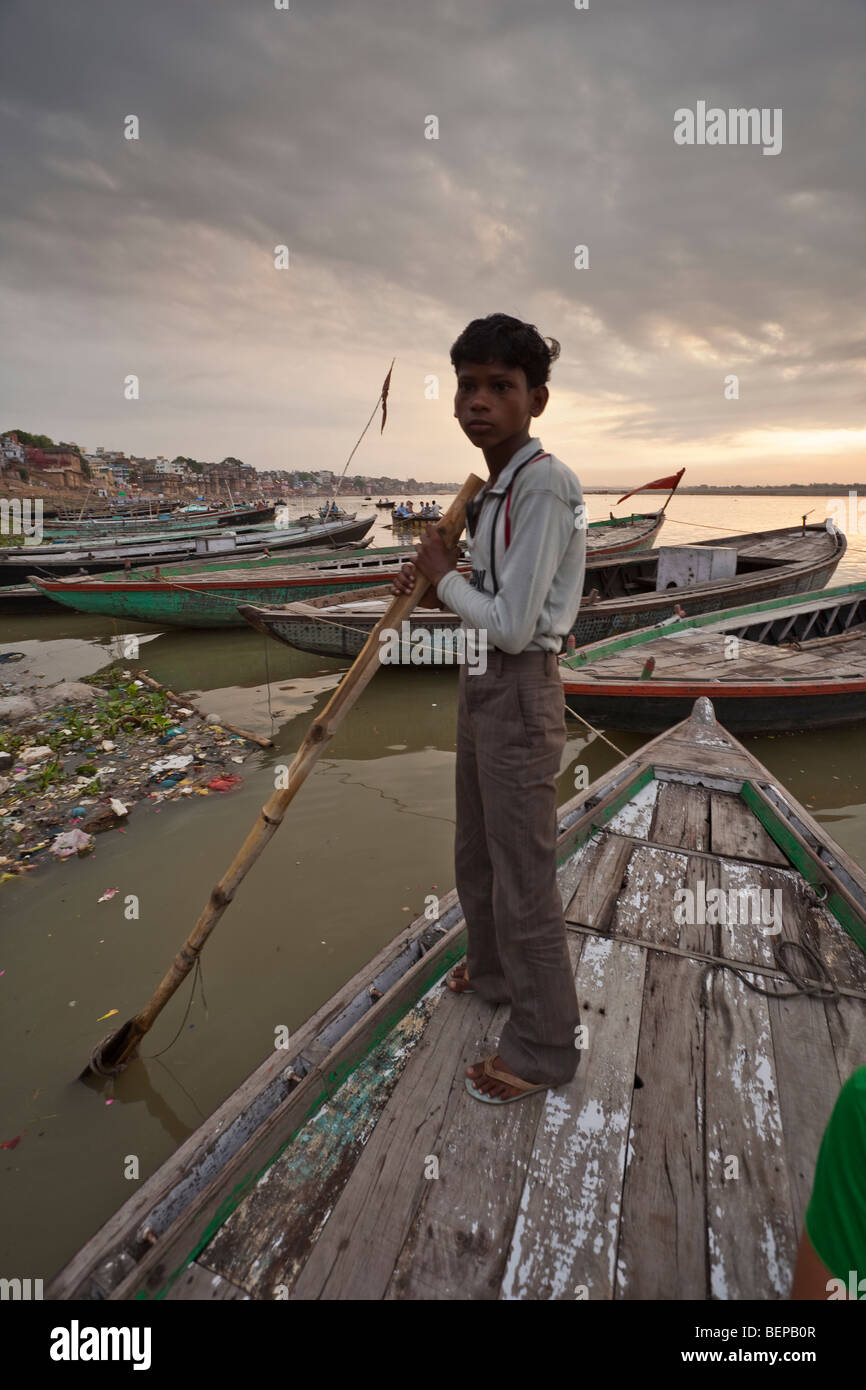 Jeune rameur attend une course jusqu'au lever du soleil sur le Gange à Varanasi, Inde Banque D'Images