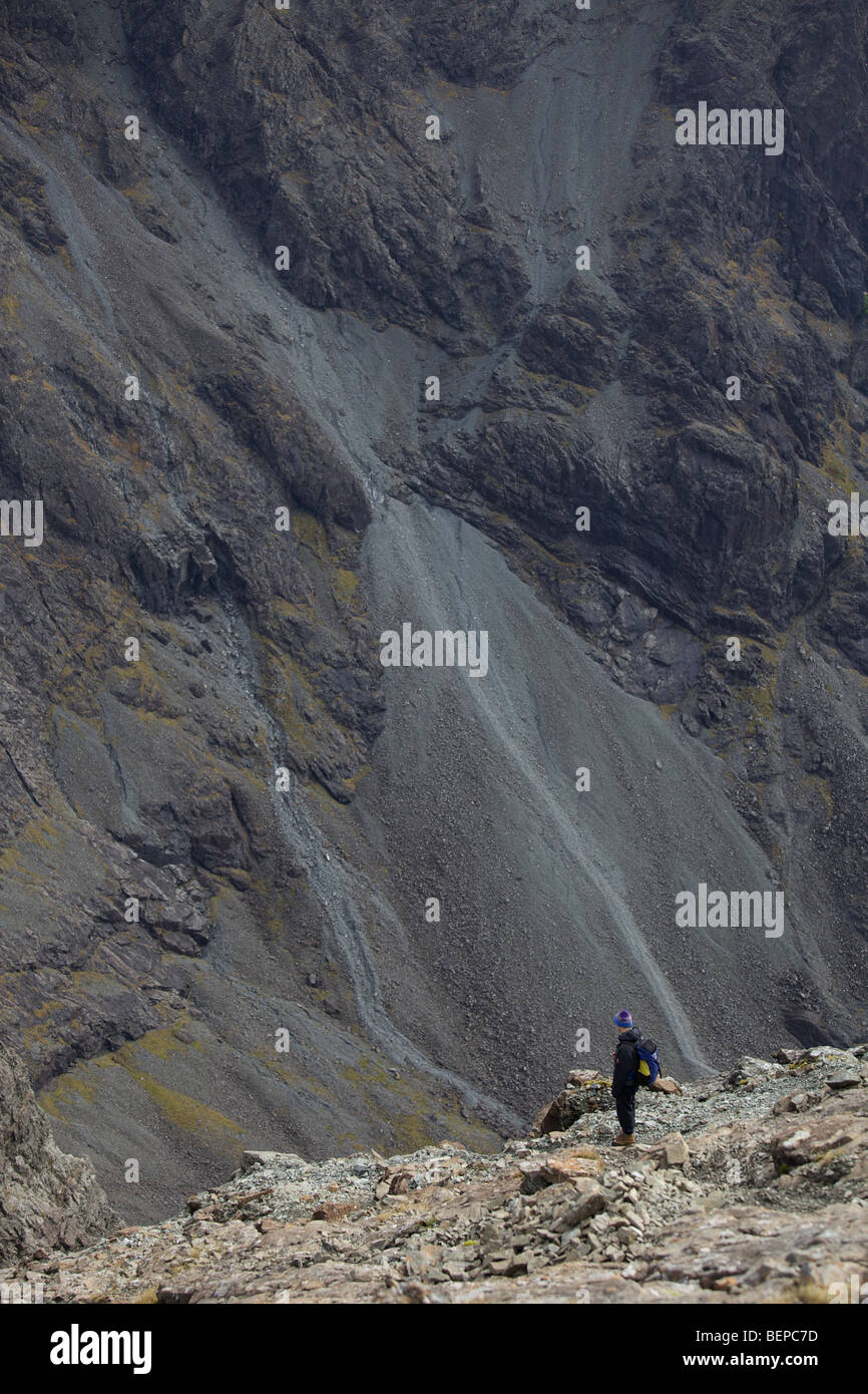 Un randonneur solitaire cherche dans une vallée profonde sur les Cuillin Ridge, Île de Skye, Écosse Banque D'Images