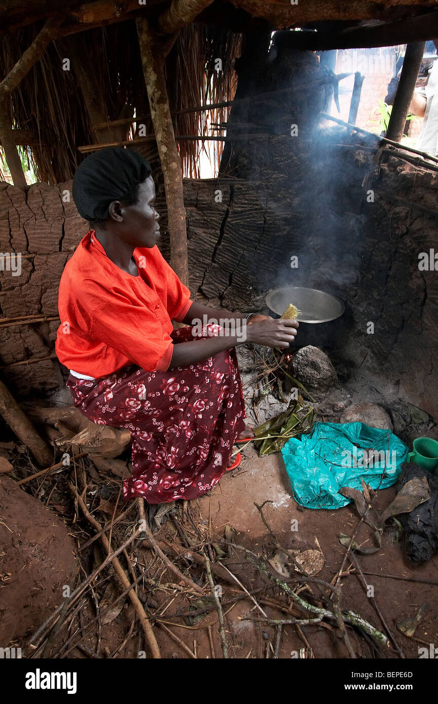 Femme de l'Ouganda en utilisant la méthode traditionnelle de cuisson sur feu ouvert dans une cuisine de Smokey. Kayunga District. PHOTO par SEAN SPRAGUE Banque D'Images
