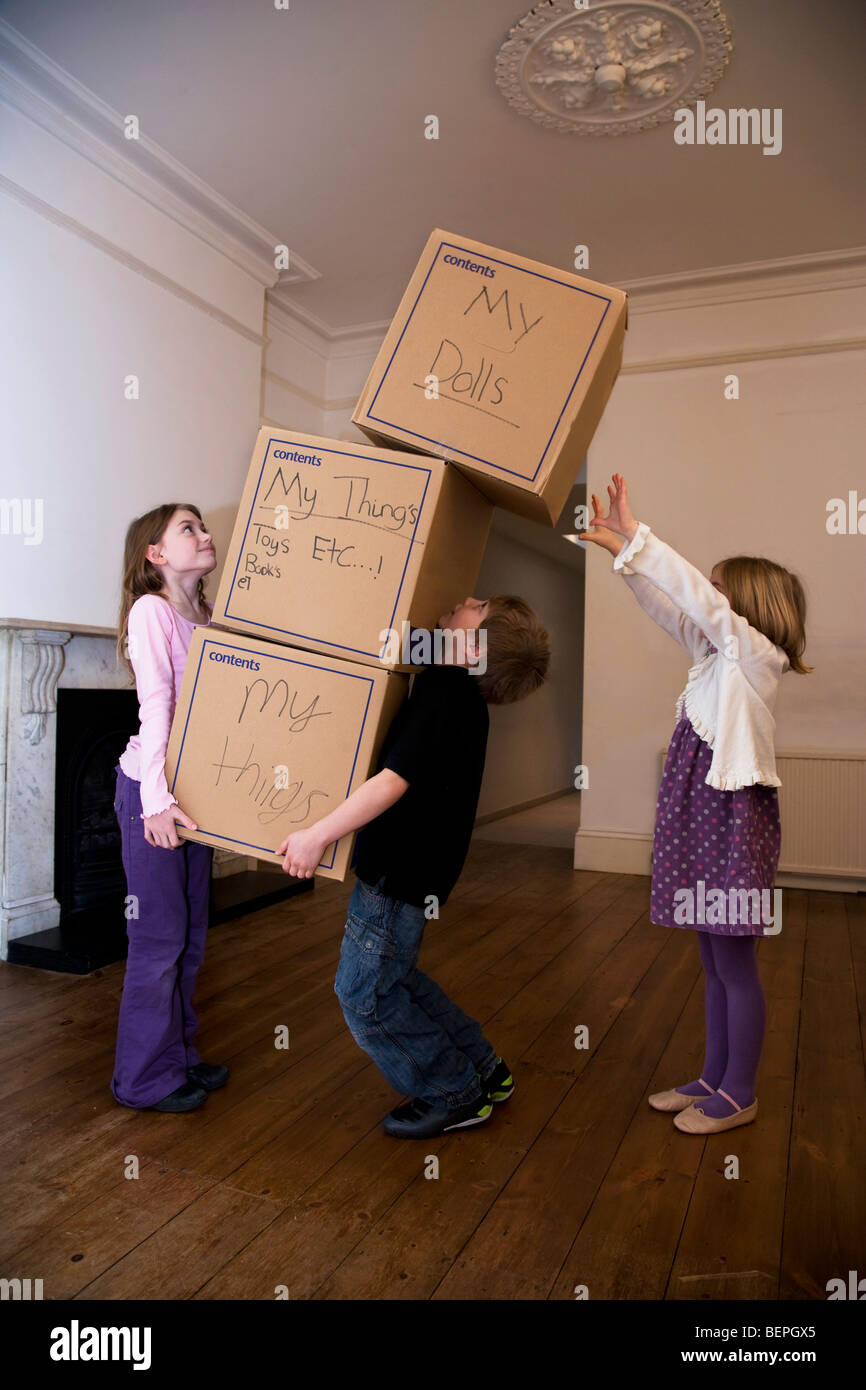 Trois enfants déménagement une pile de boîtes Banque D'Images