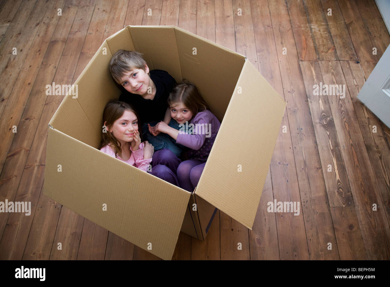 Trois enfants assis à l'intérieur d'une boîte. Banque D'Images