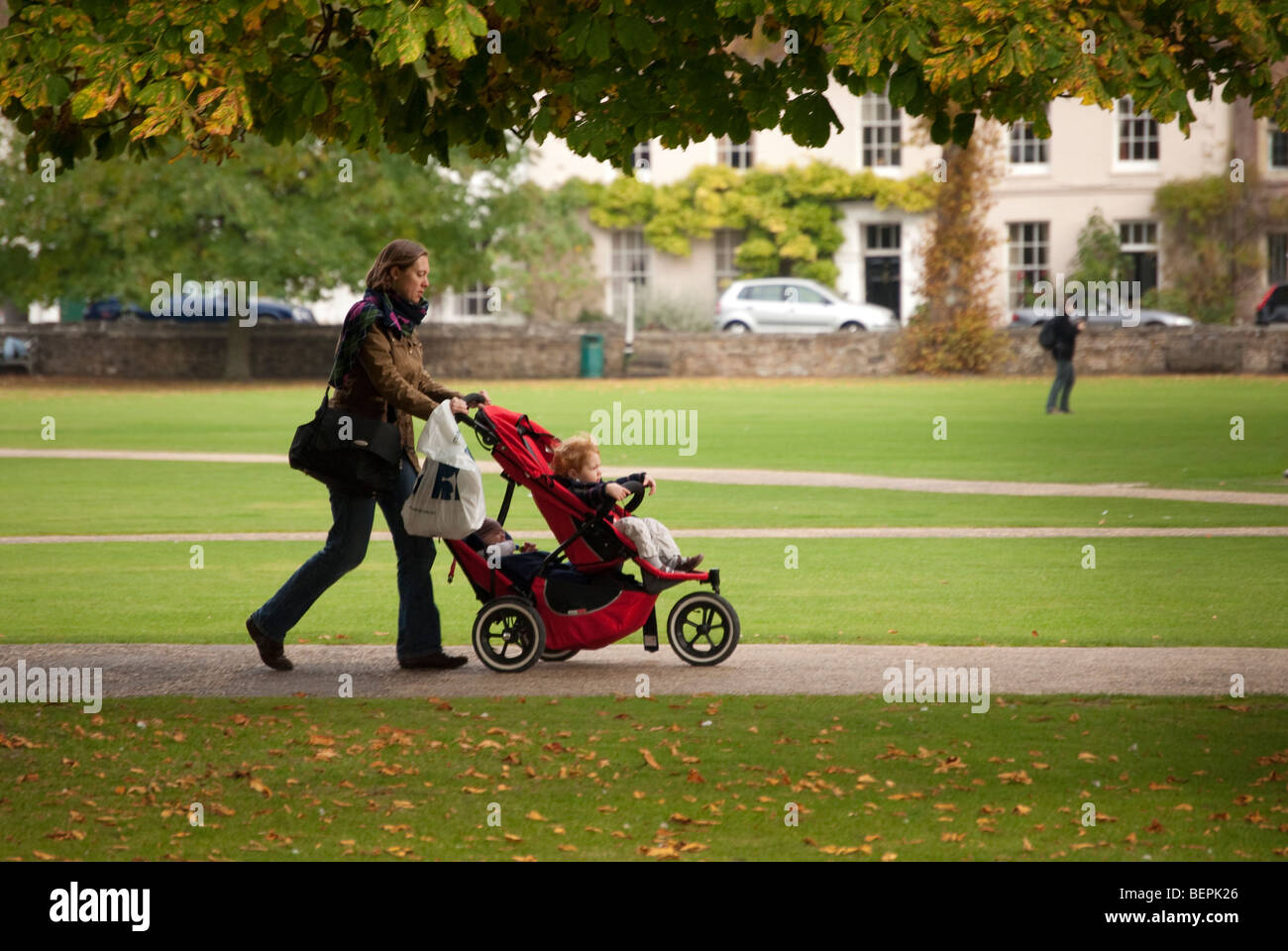 Mère de deux enfants de l'école pousse dans le parc en buggy double Banque D'Images