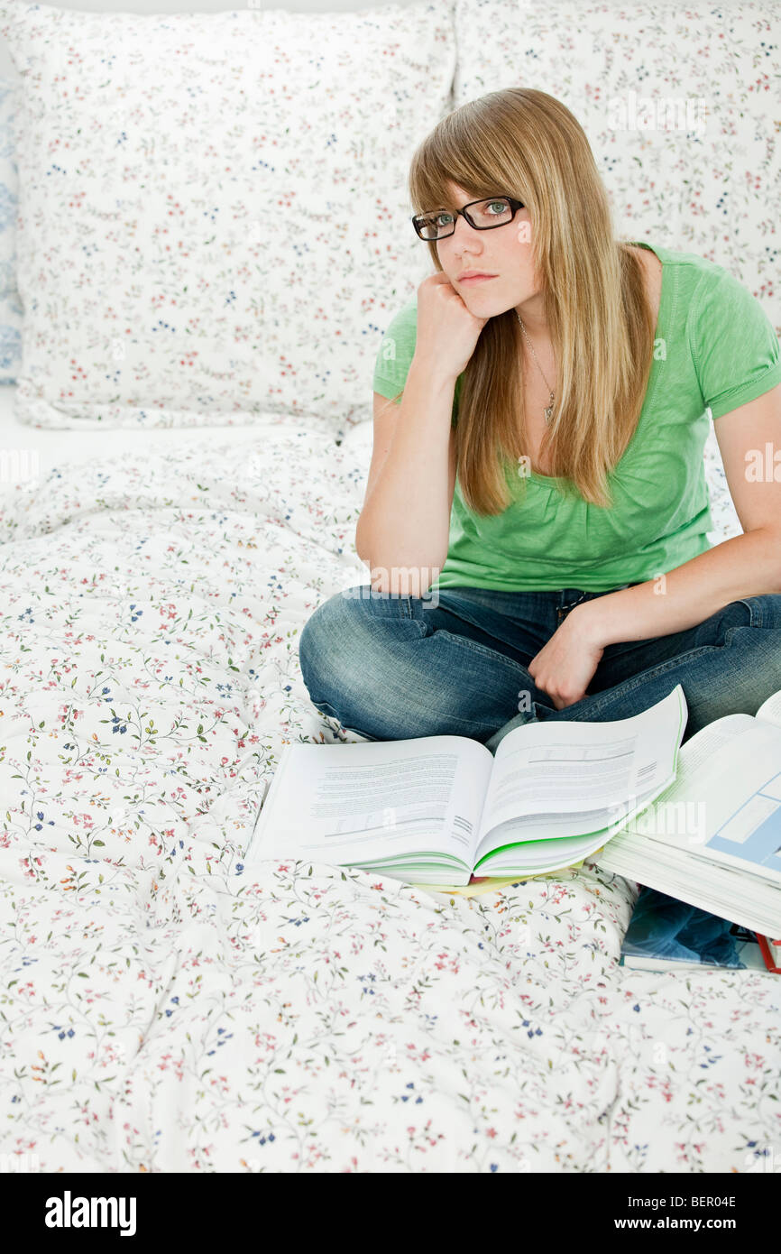 Female student sitting in bed, de l'apprentissage Banque D'Images