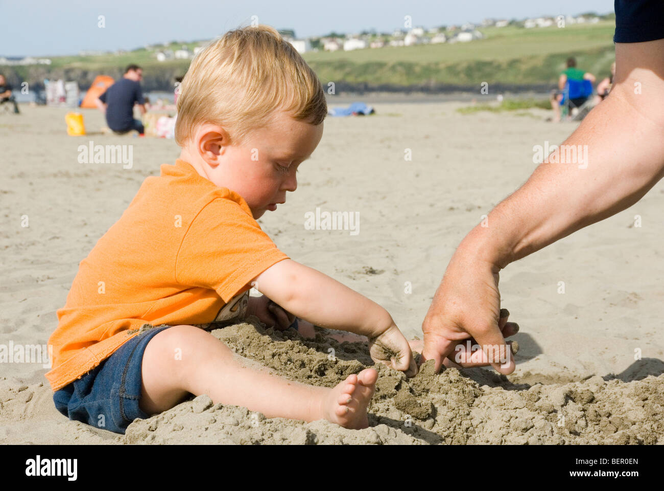 Petit garçon enfant jouant dans le sable avec son père sur la plage de sable, Pays de Galles, Poppit Banque D'Images