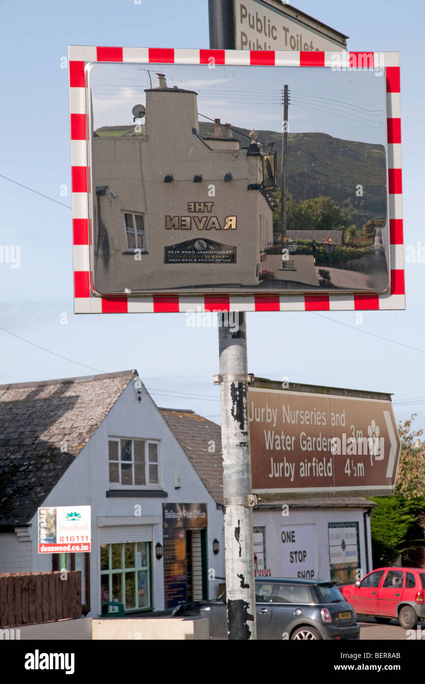 Le Corbeau pub reflétée dans un miroir de sécurité routière, monté sur un poteau de signalisation à Ballaugh villlage, partie de la célèbre TT course. Banque D'Images