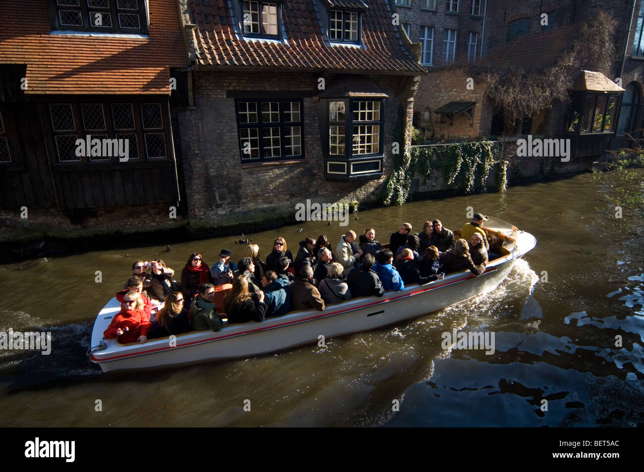 Les touristes en bateau et arrière en élévation le long canal de Bruges, Belgique Banque D'Images