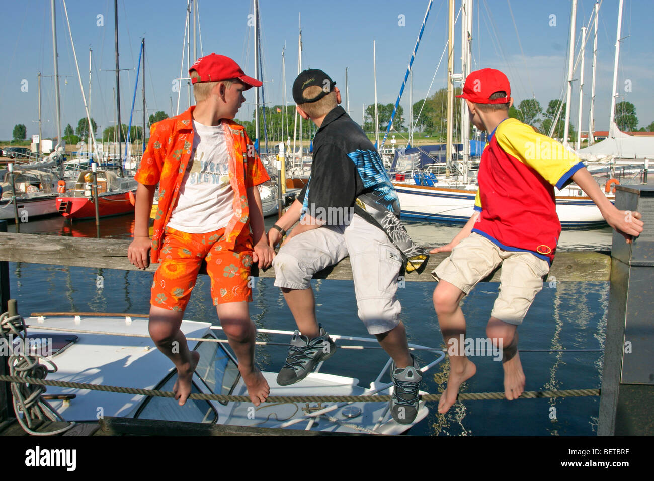 Trois jeunes garçons à la recherche à la marina de l'île de Poel, Kirchdorf, Schleswig-Holstein, Allemagne Banque D'Images