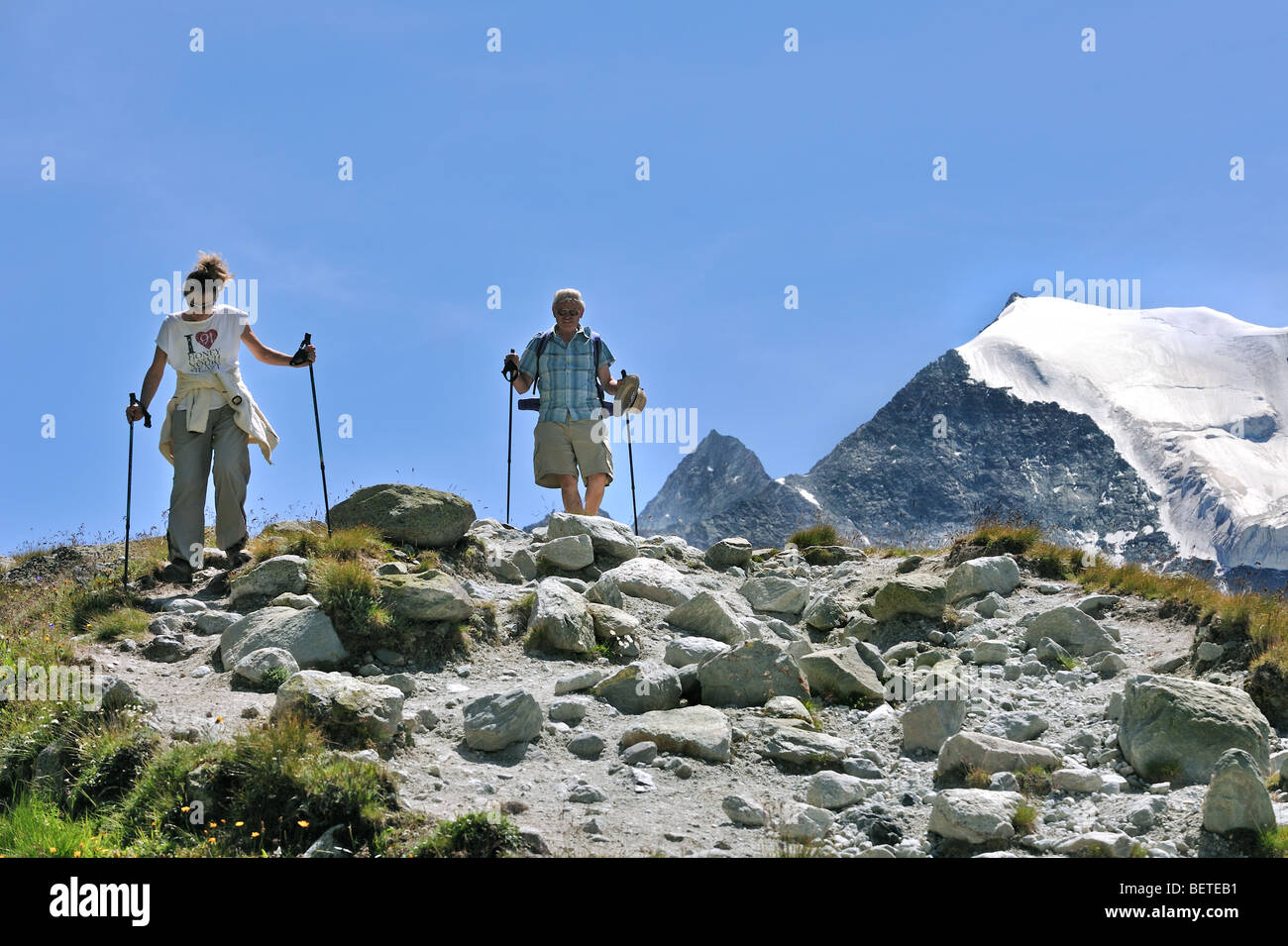 Deux touristes / marcheurs marcher le long du chemin de montagne dans les Alpes Valaisannes Suisse / Walliser Alpen, Valais / Wallis (Suisse) Banque D'Images
