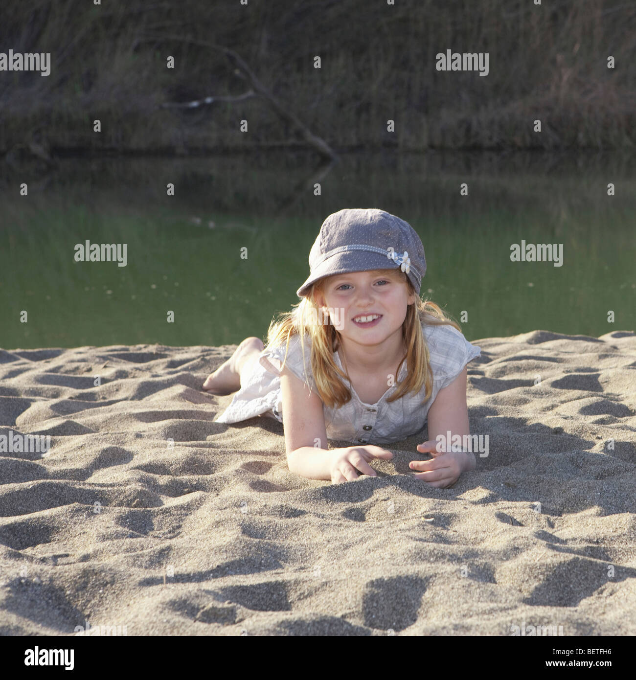 Jeune fille portant sur le sable par river Banque D'Images