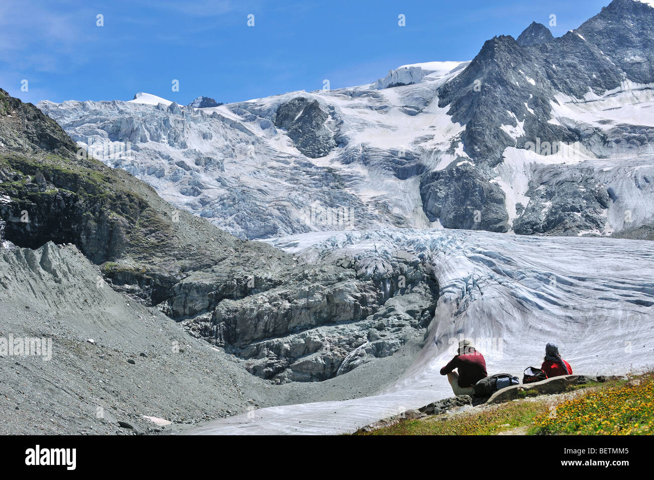 Les marcheurs / les randonneurs se reposant avec vue sur le glacier de Moiry dans les Alpes Pennines / Walliser Alpen, Valais / Wallis (Suisse) Banque D'Images