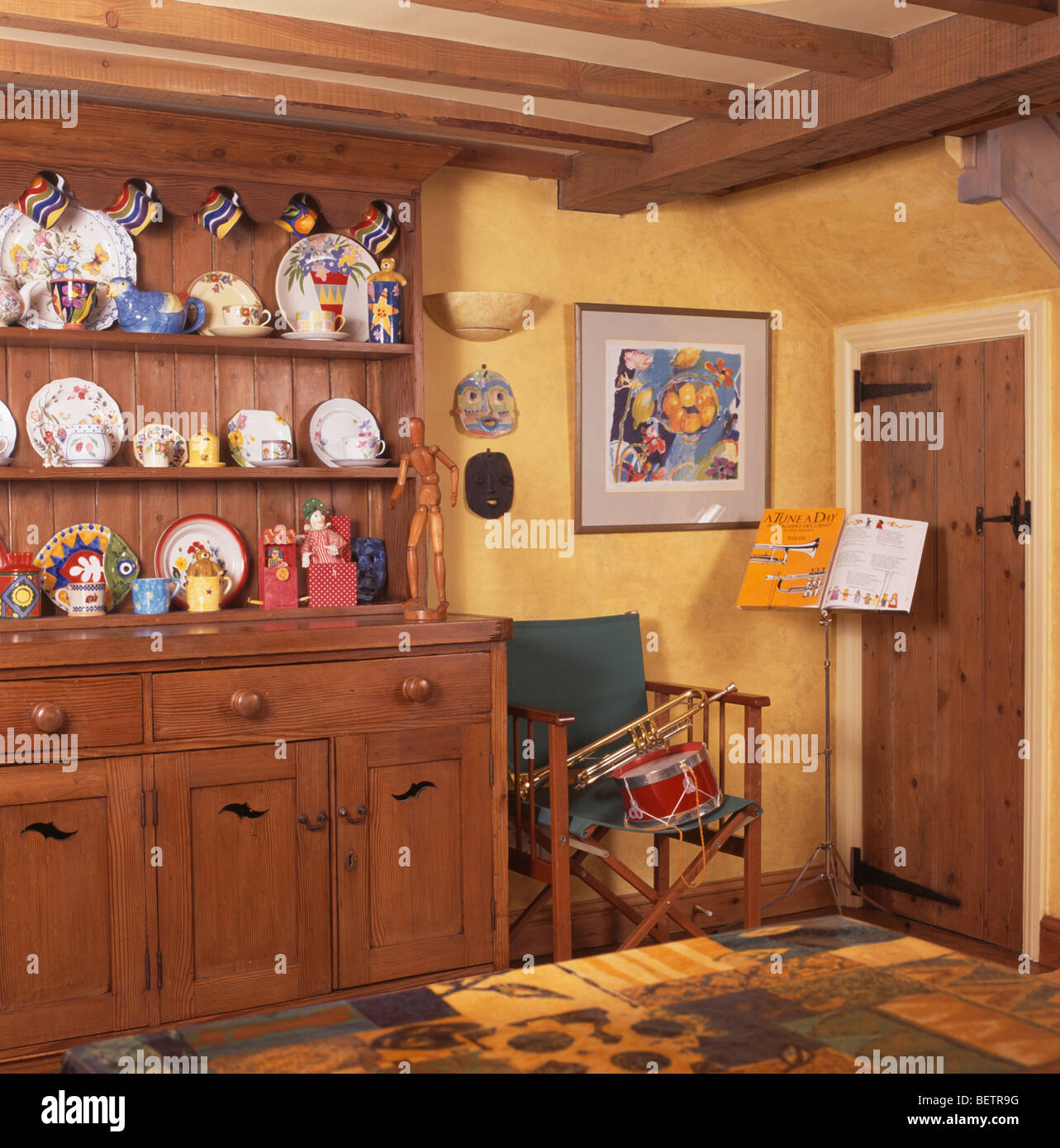 Vaisselier en pin cottage jaune salle à manger avec support musical à côté fauteuil au coin de la chambre Banque D'Images