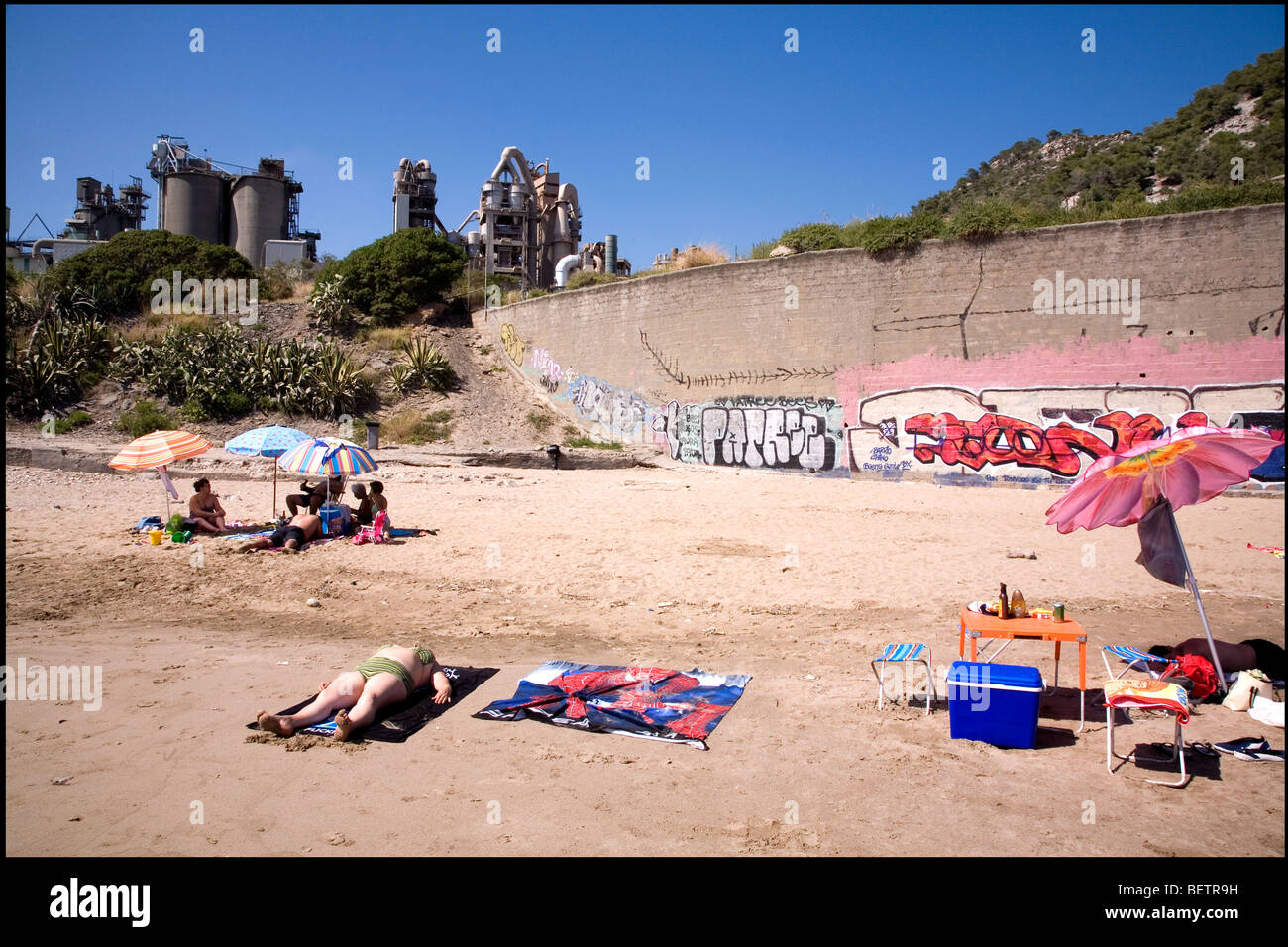 Les gens de soleil et d'avoir un pique-nique à la plage de la côte de garraf à industrielle, près de Barcelone. Banque D'Images