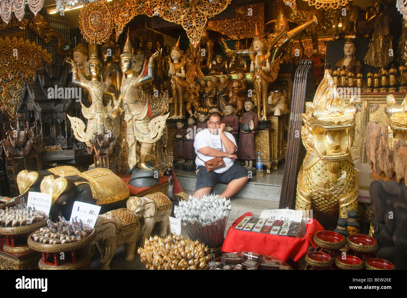 Merchant assis parmi ses statues de Bouddha au Marché du week-end de Chatuchak à Bangkok en Thaïlande Banque D'Images