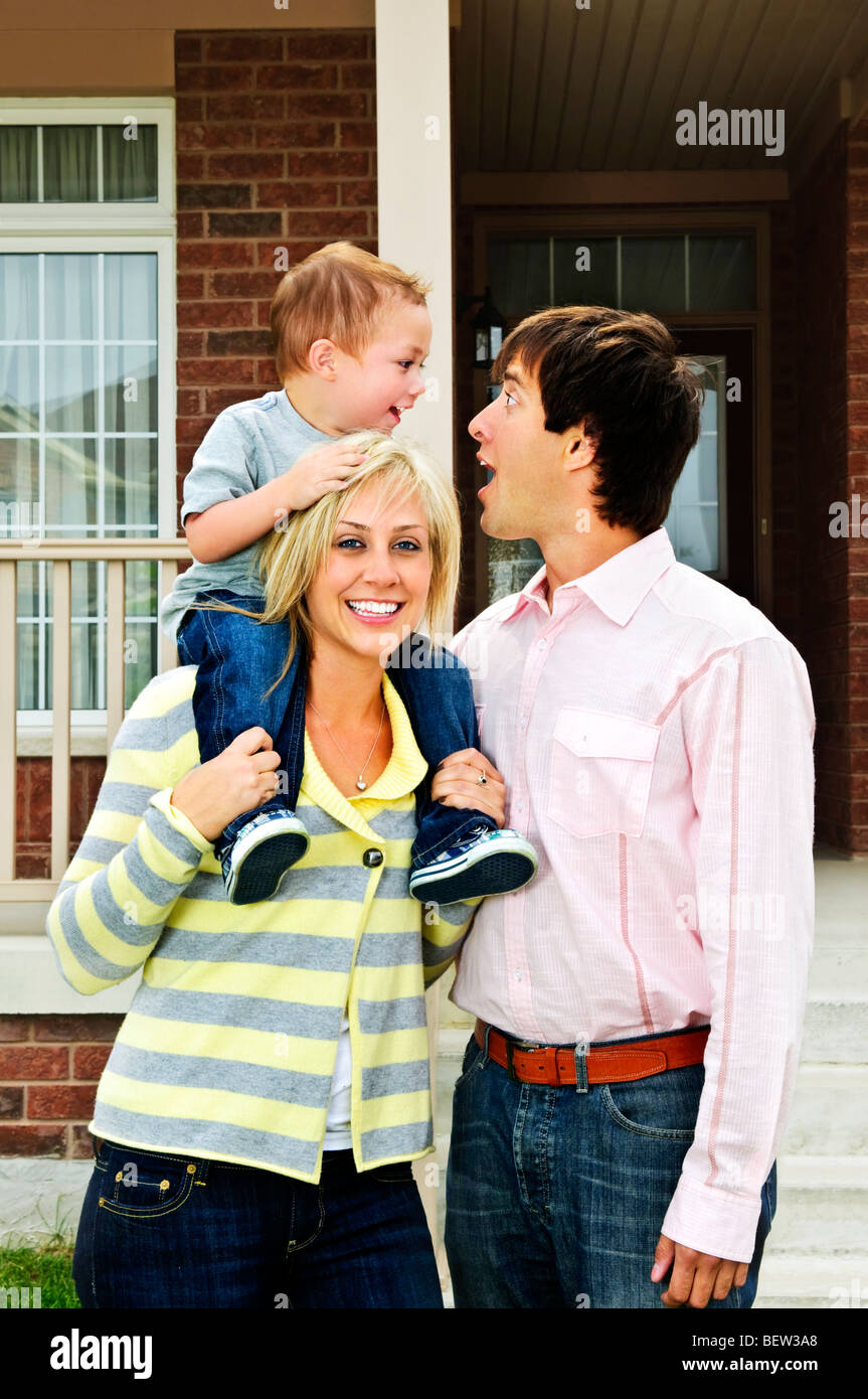 Young happy family standing in front of new home Banque D'Images