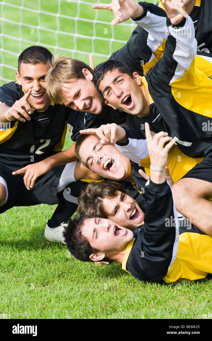 Joueurs de football cheering in face d'un poteau de but dans un terrain de soccer Banque D'Images