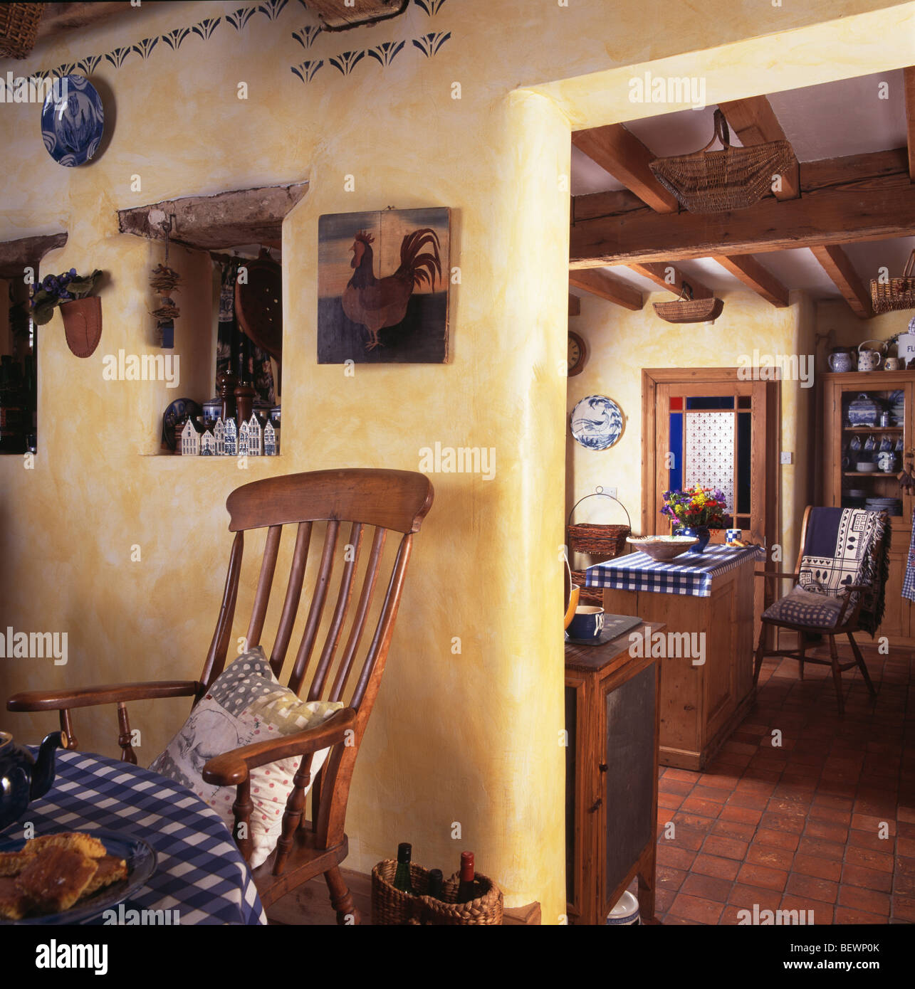 Effet-éponge peint des murs jaunes en cottage salle à manger avec chaise à côté de la vieille porte de cuisine Banque D'Images