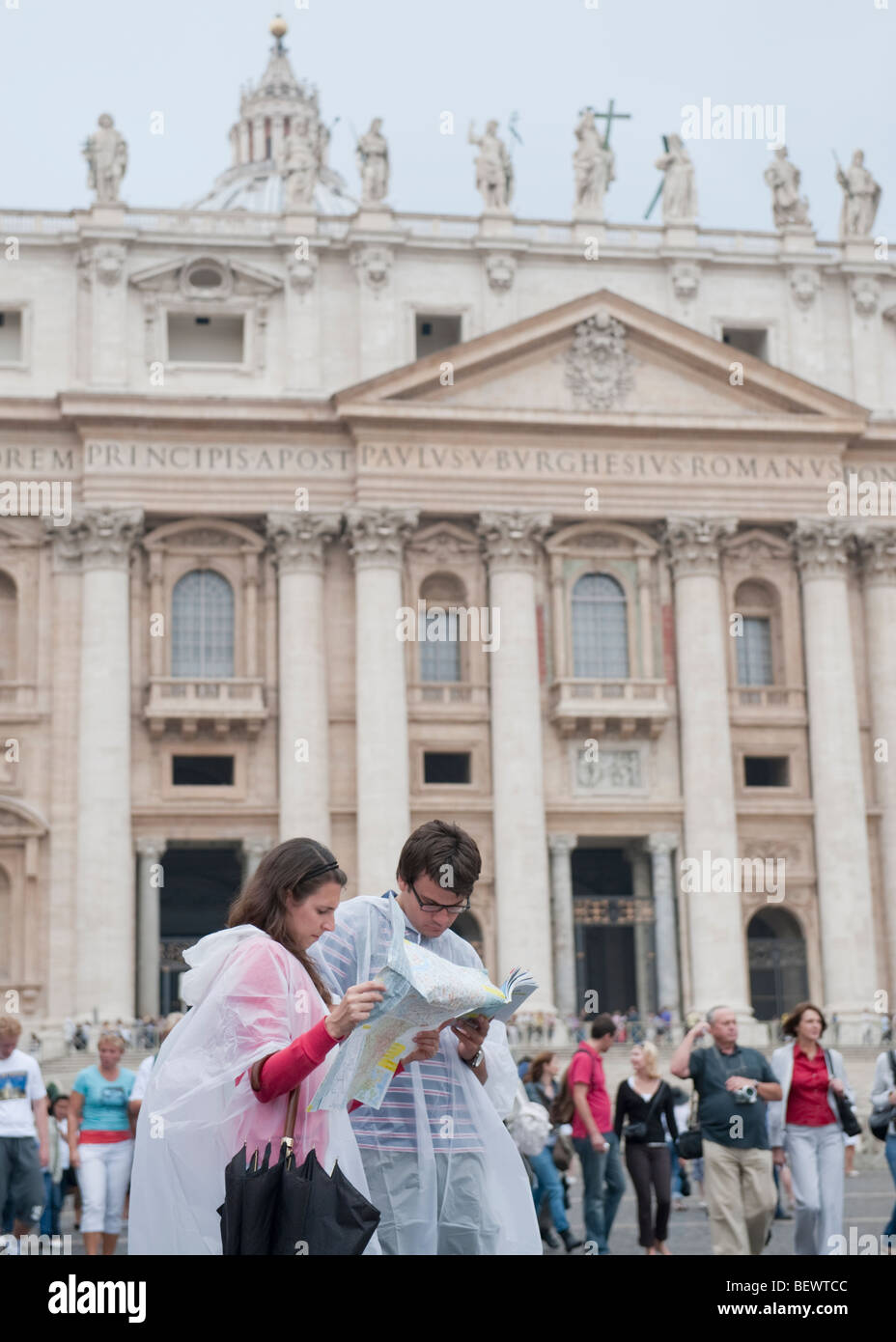 Un jeune couple de pluie explorer une carte à l'extérieur de la basilique St Pierre dans la Cité du Vatican, Rome, Italie Banque D'Images